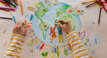 A schoolchild draws an earth in a social studies classroom, symbolizing diversity and internationalism.